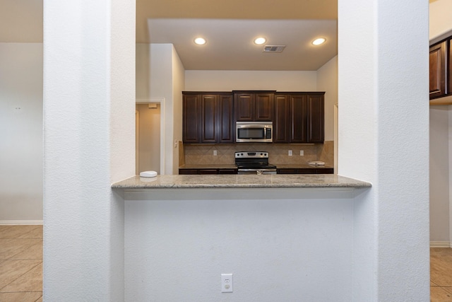 2111 Rains County Rd, Forney, TX 75126 - kitchen with appliances with stainless steel finishes, light tile patterned flooring, backsplash, dark brown cabinets, and a peninsula