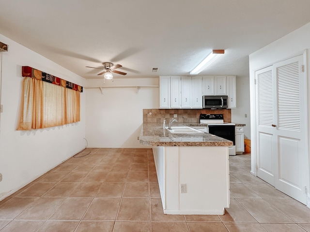 220 Hampton Ave, Corsicana, TX 75110 - kitchen with stainless steel microwave, white range with electric stovetop, tile counters, white cabinets, and light tile patterned floors