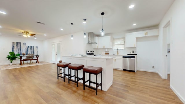 1608 Holt St, Fort Worth, TX 76103 - kitchen with stainless steel dishwasher, a breakfast bar, wall chimney exhaust hood, white cabinetry, and light wood-type flooring