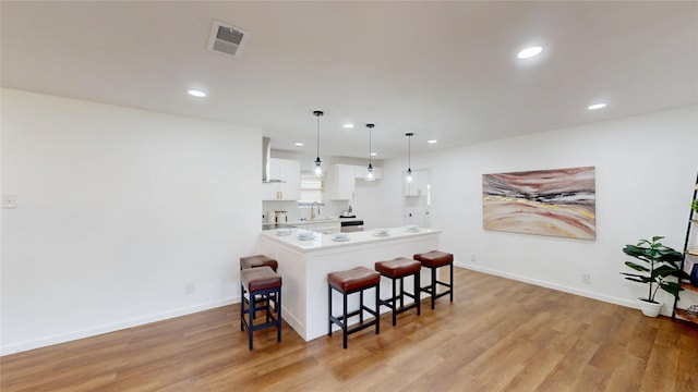 1608 Holt St, Fort Worth, TX 76103 - kitchen with a breakfast bar, white cabinetry, light wood-style floors, recessed lighting, and light countertops