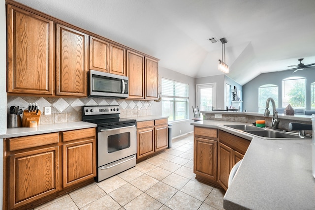 703 Monterey Dr, Rockwall, TX 75087 - kitchen featuring stainless steel appliances, lofted ceiling, decorative backsplash, healthy amount of natural light, and brown cabinets