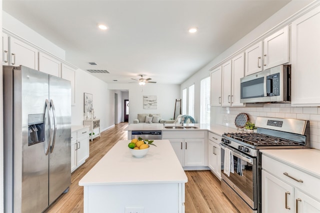 1233 Western Yarrow Ave, Justin, TX 76247 - kitchen with stainless steel appliances, open floor plan, light wood-type flooring, a ceiling fan, and a center island