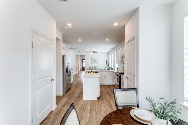 1233 Western Yarrow Ave, Justin, TX 76247 - kitchen featuring appliances with stainless steel finishes, open floor plan, white cabinetry, light wood-style floors, and a kitchen island