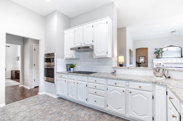 400 Patricia Ln, Highland Village, TX 75077 - kitchen featuring black electric stovetop, stainless steel double oven, under cabinet range hood, white cabinetry, and decorative backsplash