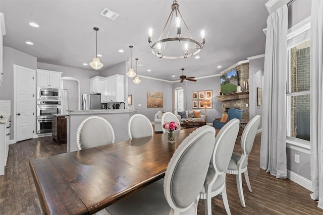 6202 Carrizo Dr, De Cordova, TX 76049 - dining area featuring ceiling fan, arched walkways, a chandelier, a fireplace, and dark wood finished floors