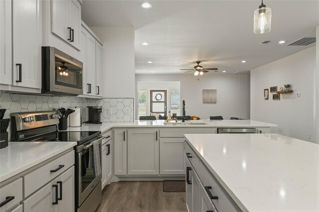 532 W Florence St, Denison, TX 75020 - kitchen featuring appliances with stainless steel finishes, ceiling fan, a peninsula, light countertops, and dark wood finished floors