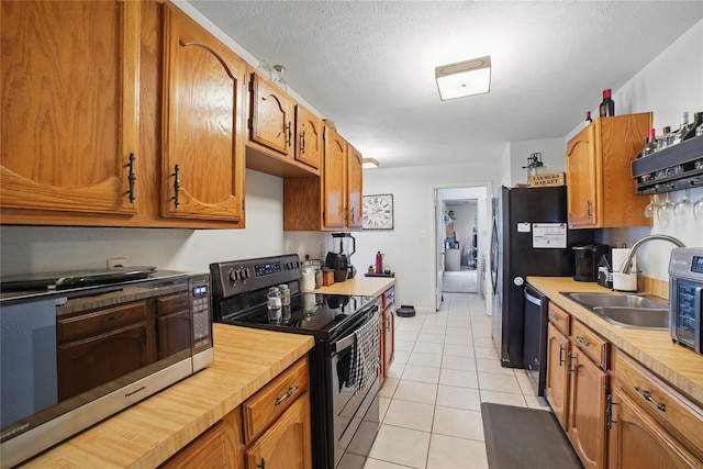 4328 Coryell Way, Mesquite, TX 75150 - kitchen with black / electric stove, stainless steel microwave, dishwashing machine, light tile patterned flooring, and brown cabinets