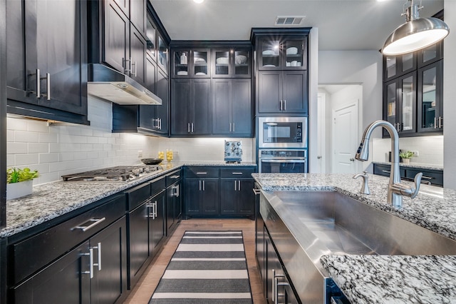 3418 River Trl, Frisco, TX 75034 - kitchen featuring appliances with stainless steel finishes, light wood-style floors, light stone counters, and decorative backsplash
