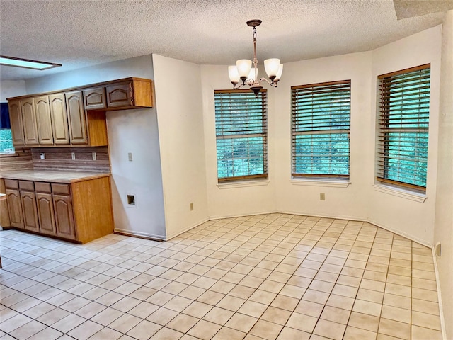 2909 Troy Rd, Wylie, TX 75098 - kitchen featuring light tile patterned floors, a chandelier, a textured ceiling, light countertops, and hanging light fixtures