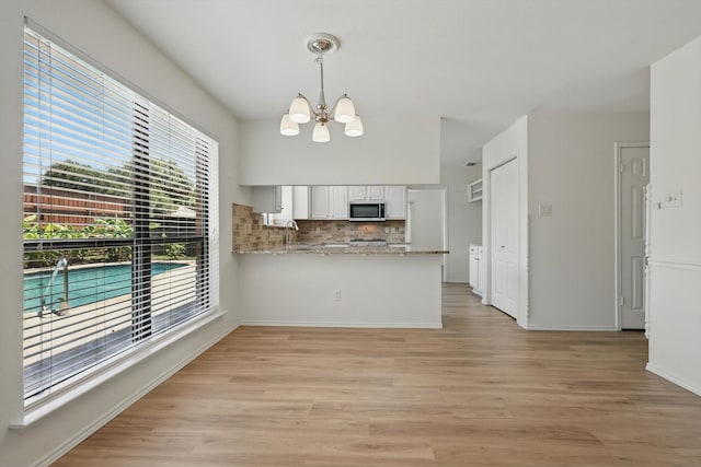 1800 Chatham Dr, Flower Mound, TX 75028 - kitchen featuring stainless steel microwave, a chandelier, healthy amount of natural light, and tasteful backsplash