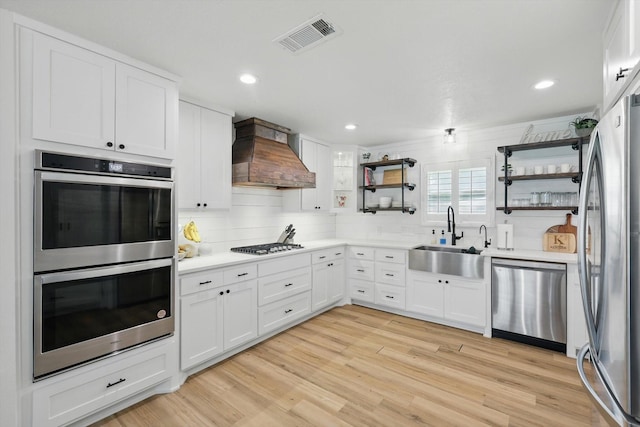 600 Reese Ln, Azle, TX 76020 - kitchen with appliances with stainless steel finishes, custom range hood, open shelves, backsplash, and white cabinetry