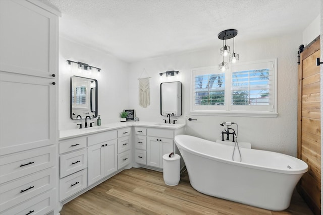 600 Reese Ln, Azle, TX 76020 - full bath with double vanity, a freestanding tub, a textured ceiling, and wood finished floors