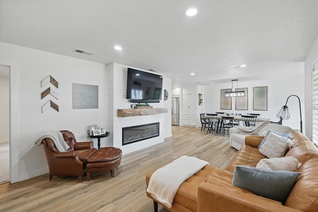 600 Reese Ln, Azle, TX 76020 - living room with a glass covered fireplace, light wood finished floors, recessed lighting, and a chandelier