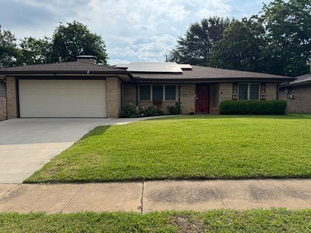 2329 Diana Dr, Sherman, TX 75092 - view of front of home with a garage, a front lawn, roof mounted solar panels, concrete driveway, and brick siding