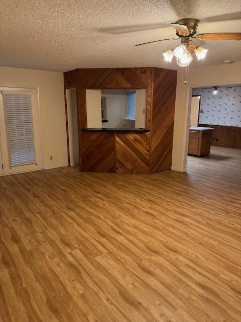2329 Diana Dr, Sherman, TX 75092 - unfurnished living room featuring a textured ceiling, light wood-style floors, ceiling fan, and wood walls
