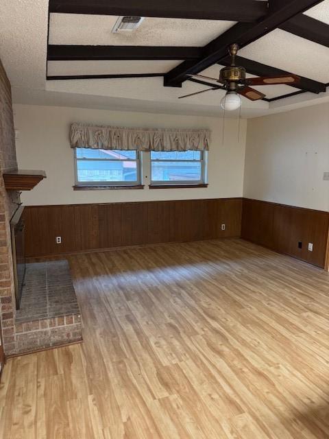 2329 Diana Dr, Sherman, TX 75092 - unfurnished living room featuring wainscoting, wood finished floors, wooden walls, a ceiling fan, and beamed ceiling