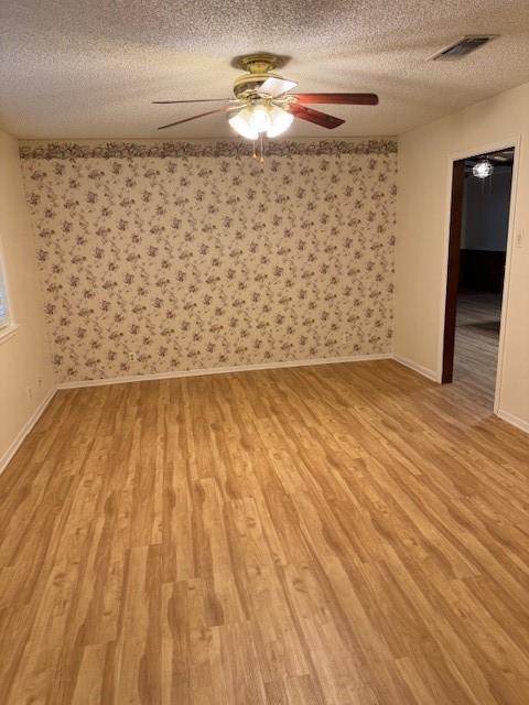 2329 Diana Dr, Sherman, TX 75092 - spare room featuring a textured ceiling, light wood finished floors, ceiling fan, and wallpapered walls