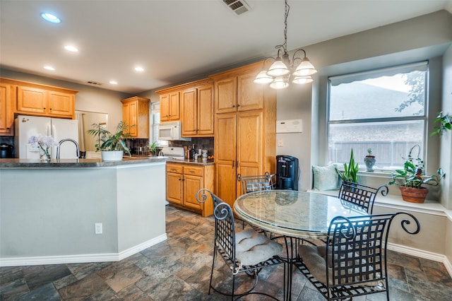 3209 Windridge Ln, Corinth, TX 76208 - kitchen featuring white microwave, freestanding refrigerator, stone tile flooring, hanging light fixtures, and recessed lighting