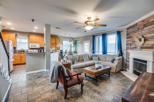 3209 Windridge Ln, Corinth, TX 76208 - living area featuring ceiling fan, plenty of natural light, a glass covered fireplace, stone finish flooring, and crown molding
