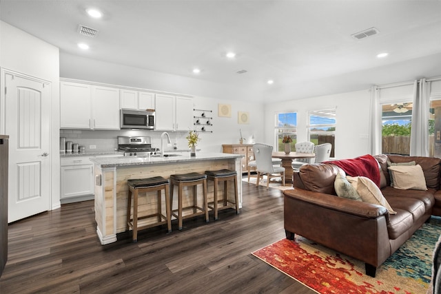 9200 S Field Ln, Arlington, TX 76002 - kitchen with appliances with stainless steel finishes, dark wood finished floors, a kitchen bar, open floor plan, and recessed lighting