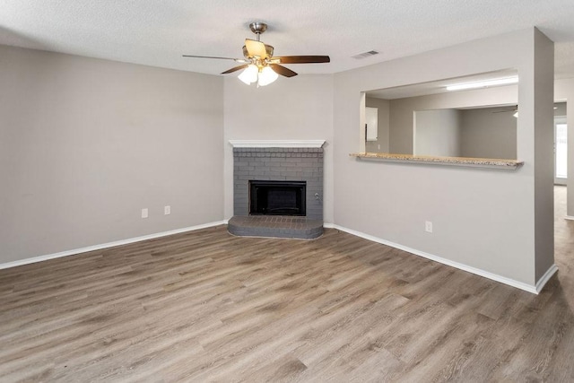 1449 Saint Gallen Ln, Lewisville, TX 75067 - unfurnished living room featuring ceiling fan, wood finished floors, a brick fireplace, and a textured ceiling