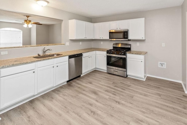 1449 Saint Gallen Ln, Lewisville, TX 75067 - kitchen featuring stainless steel appliances, white cabinets, light wood-style floors, a ceiling fan, and light stone countertops