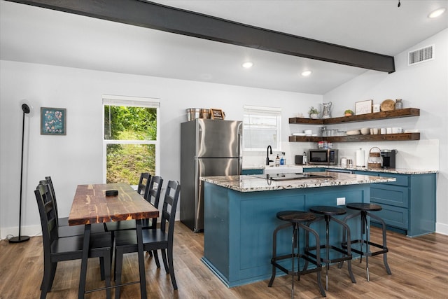 5986 Field Ct, Granbury, TX 76048 - kitchen featuring appliances with stainless steel finishes, open shelves, blue cabinets, a kitchen island, and wood finished floors