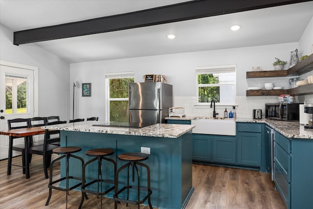 5986 Field Ct, Granbury, TX 76048 - kitchen with stainless steel appliances, blue cabinets, open shelves, healthy amount of natural light, and beam ceiling
