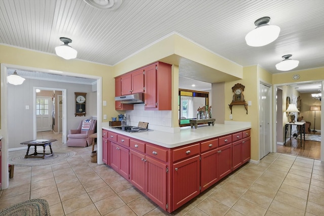 1615 Lopo Rd, Flower Mound, TX 75028 - kitchen with under cabinet range hood, stainless steel cooktop, light tile patterned floors, light countertops, and backsplash