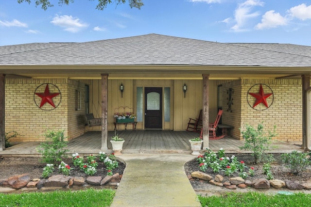 1615 Lopo Rd, Flower Mound, TX 75028 - view of exterior entry featuring roof with shingles, brick siding, a porch, and board and batten siding