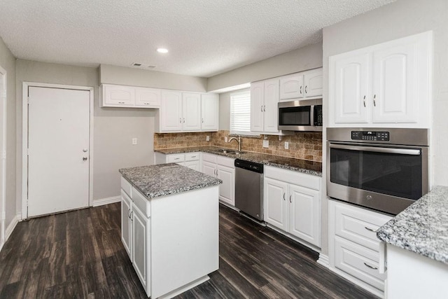6908 Briardale Dr, North Richland Hills, TX 76182 - kitchen featuring stainless steel appliances, dark stone countertops, dark wood-style flooring, decorative backsplash, and a textured ceiling