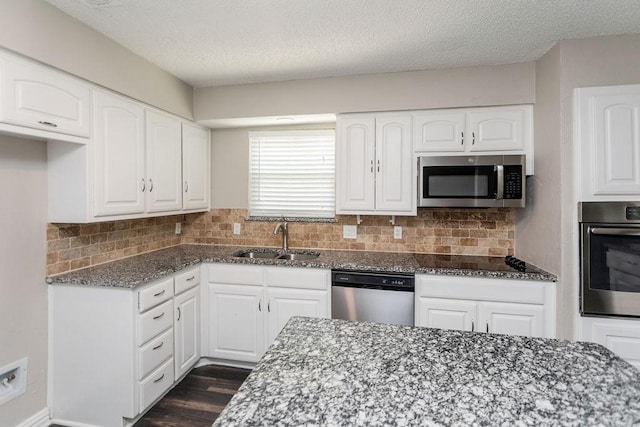 6908 Briardale Dr, North Richland Hills, TX 76182 - kitchen with appliances with stainless steel finishes, dark stone countertops, white cabinets, decorative backsplash, and a textured ceiling