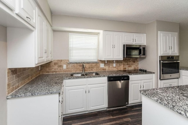 6908 Briardale Dr, North Richland Hills, TX 76182 - kitchen featuring appliances with stainless steel finishes, dark stone countertops, dark wood-style flooring, white cabinetry, and tasteful backsplash