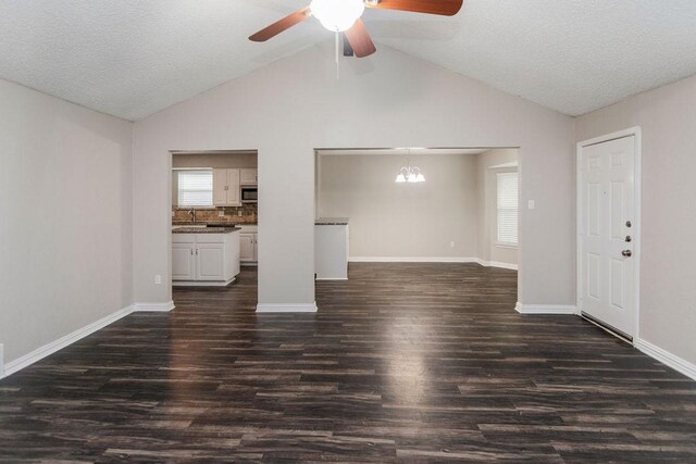 6908 Briardale Dr, North Richland Hills, TX 76182 - unfurnished living room with vaulted ceiling, dark wood-style floors, ceiling fan, and a chandelier