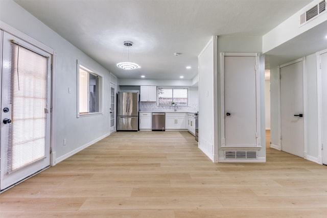 2018 Vail Dr, Garland, TX 75044 - kitchen with appliances with stainless steel finishes, white cabinetry, light wood-type flooring, pendant lighting, and light countertops
