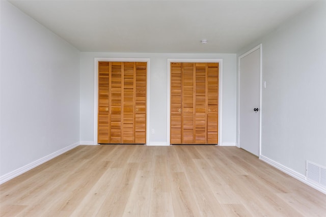 2018 Vail Dr, Garland, TX 75044 - unfurnished bedroom with light wood-type flooring and two closets