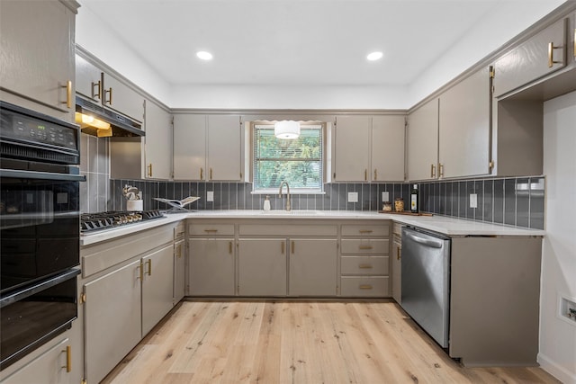 1813 Madera Dr, Waco, TX 76705 - kitchen featuring stainless steel appliances, a warming drawer, under cabinet range hood, light wood finished floors, and decorative backsplash