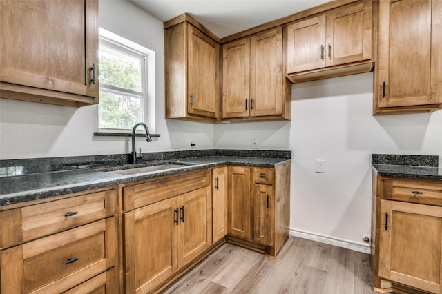 2775 E Overton Rd, Dallas, TX 75216 - kitchen with light wood-type flooring, dark stone counters, and brown cabinets