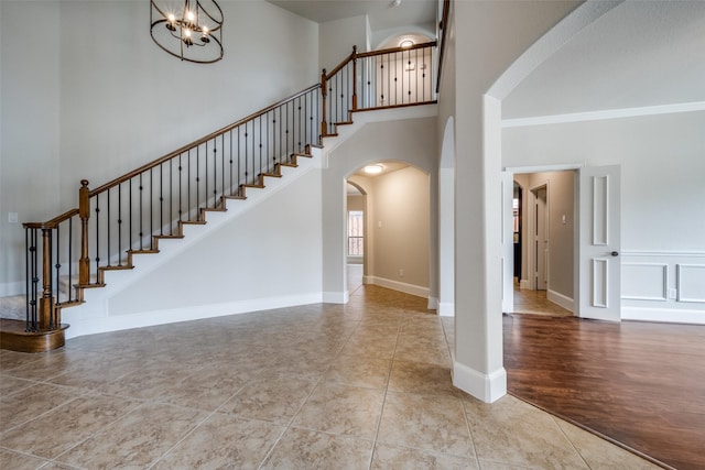 1909 Rocky Ct, Corinth, TX 76208 - staircase featuring arched walkways, a chandelier, a towering ceiling, and tile patterned floors