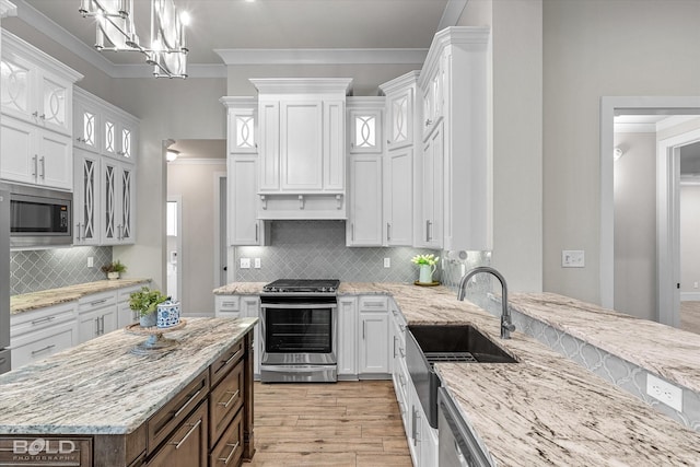 140 St Andrews Ln, Benton, LA 71006 - kitchen with stainless steel appliances, white cabinets, crown molding, light wood-style flooring, and tasteful backsplash