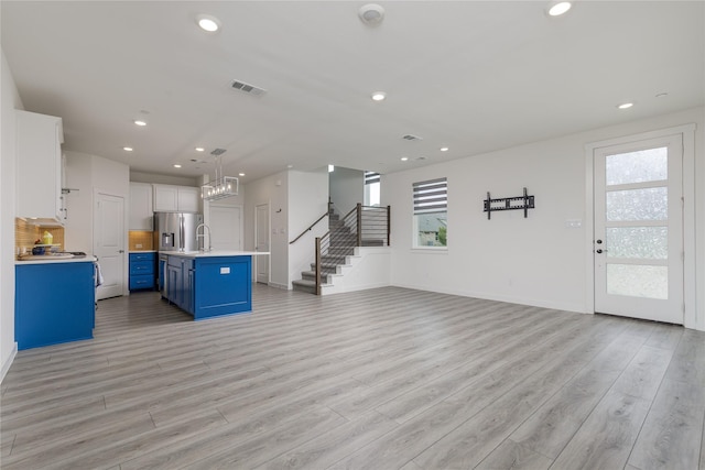 3811 Pine Leaf Ln, Prosper, TX 75078 - unfurnished living room with plenty of natural light, recessed lighting, light wood-style floors, and stairs