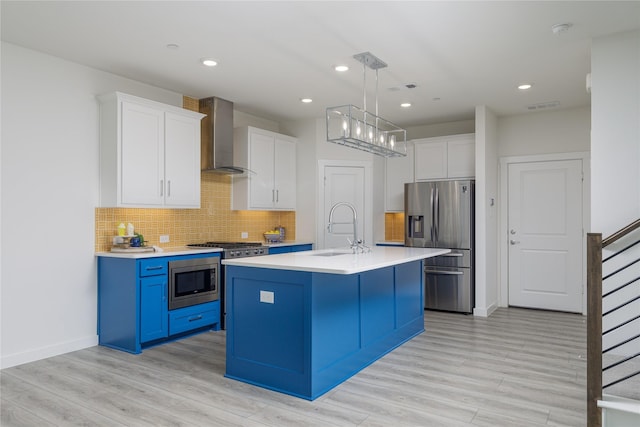3811 Pine Leaf Ln, Prosper, TX 75078 - kitchen with stainless steel appliances, wall chimney range hood, light countertops, light wood-style floors, and white cabinets