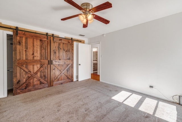 733 N Willis St, Abilene, TX 79603 - unfurnished bedroom with a barn door, carpet flooring, and ceiling fan
