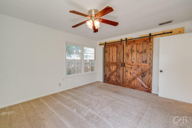 733 N Willis St, Abilene, TX 79603 - unfurnished bedroom featuring a barn door, carpet flooring, and a ceiling fan