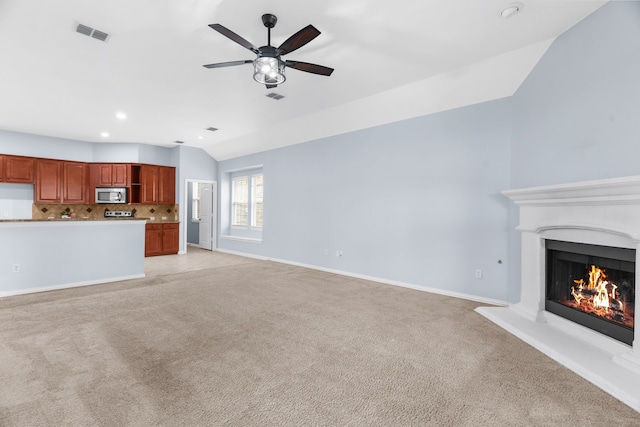 10305 Matador Dr, Mckinney, TX 75072 - unfurnished living room with light carpet, vaulted ceiling, a warm lit fireplace, ceiling fan, and recessed lighting