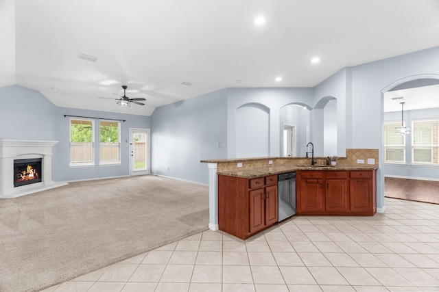 10305 Matador Dr, Mckinney, TX 75072 - kitchen featuring dishwasher, a ceiling fan, brown cabinetry, a lit fireplace, and lofted ceiling