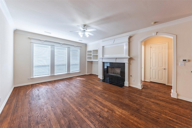 220 Justin Rd, Murphy, TX 75094 - unfurnished living room featuring ceiling fan, dark wood-style flooring, ornamental molding, a tiled fireplace, and arched walkways