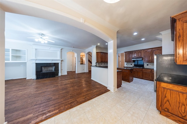 220 Justin Rd, Murphy, TX 75094 - kitchen featuring arched walkways, open floor plan, crown molding, ceiling fan, and backsplash