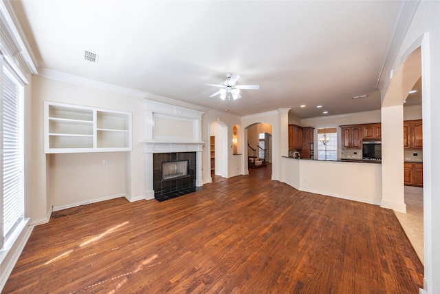 220 Justin Rd, Murphy, TX 75094 - unfurnished living room with arched walkways, ornamental molding, a tile fireplace, a ceiling fan, and dark wood-type flooring
