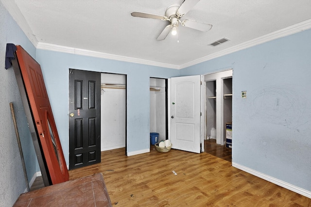 3832 Mount Ranier St, Dallas, TX 75211 - unfurnished bedroom featuring two closets, ornamental molding, light wood finished floors, and a ceiling fan